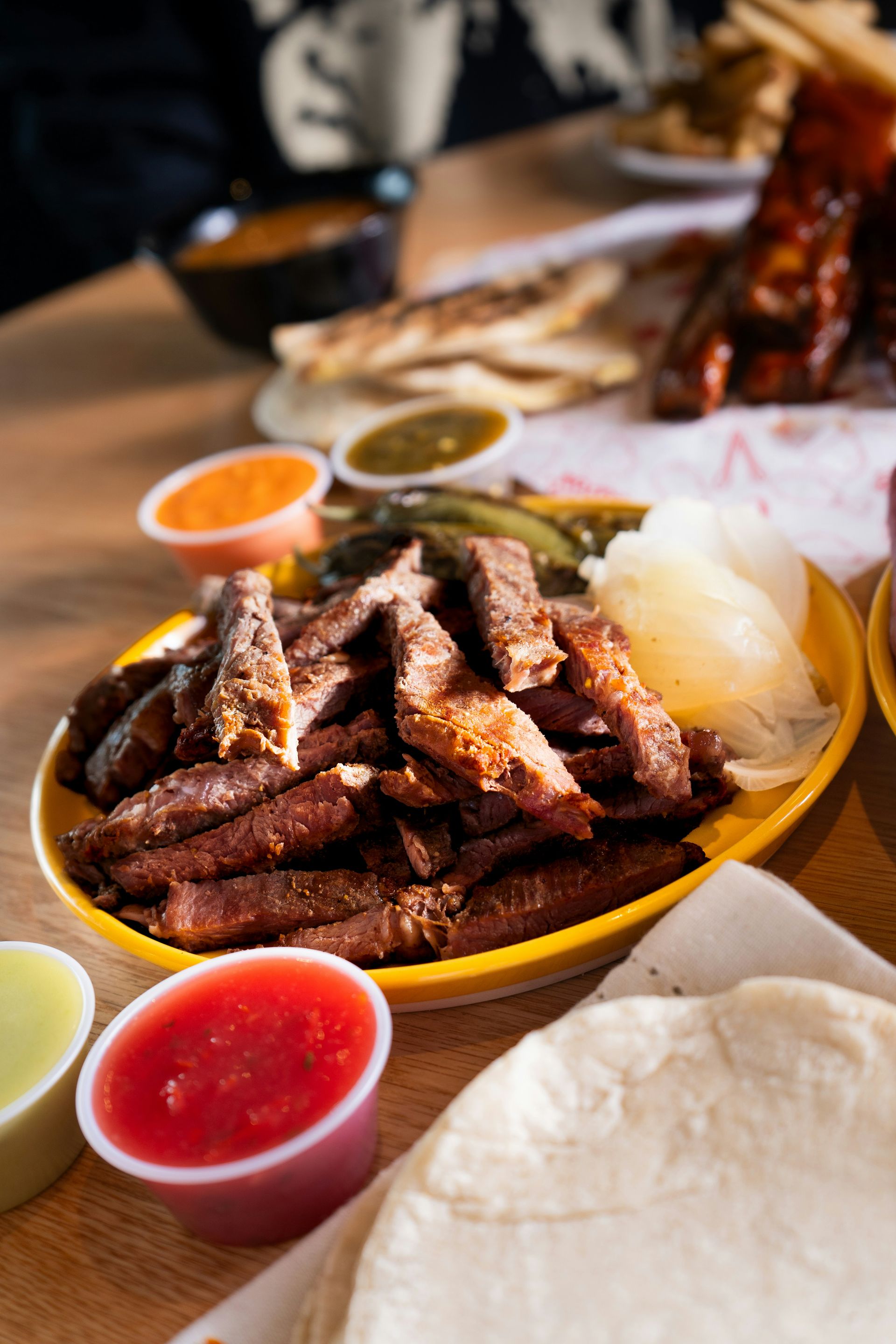 Carne asada with salsas, tortillas, and pickled onions