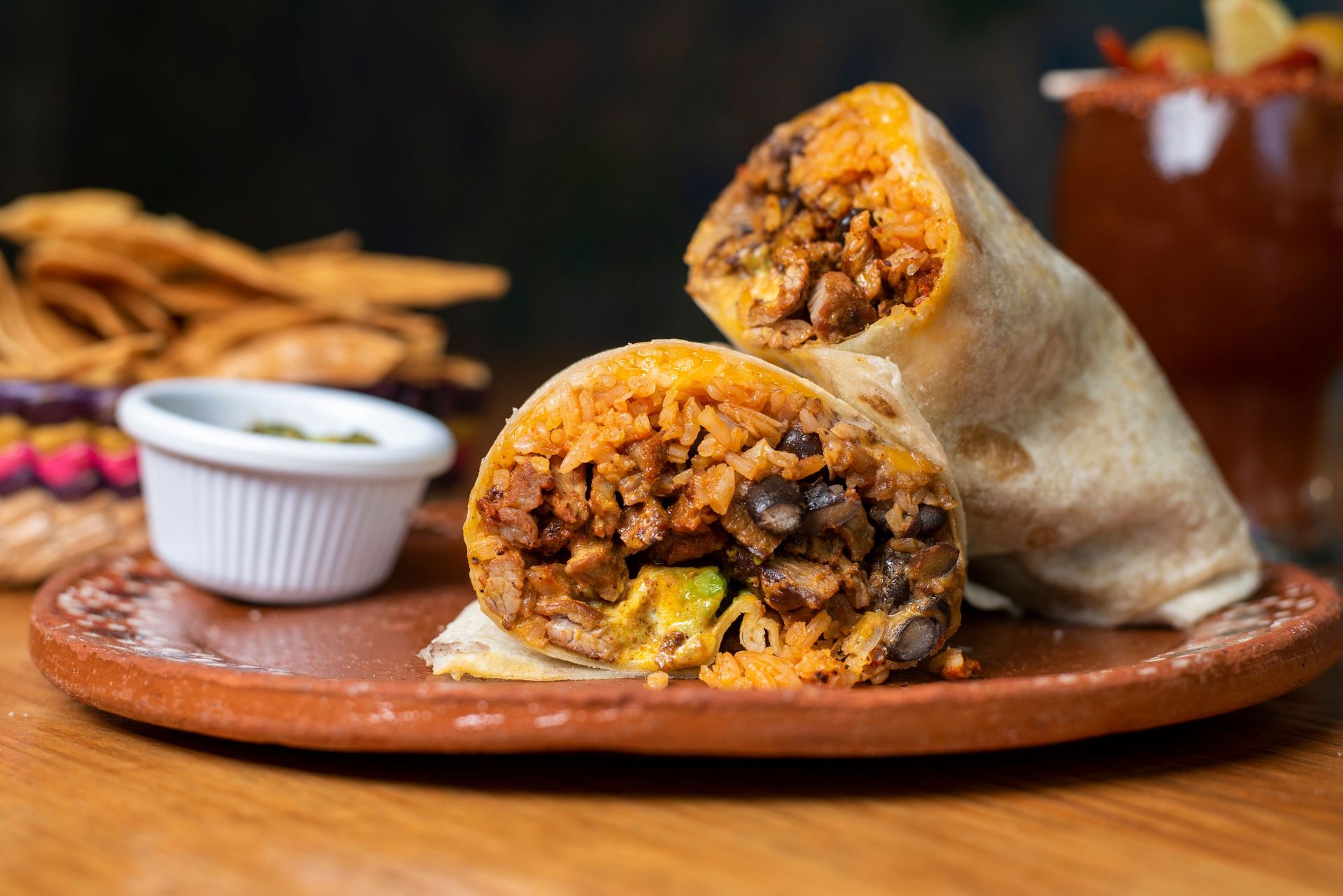 Mouthwatering beef and rice burrito served on a rustic plate with chips.